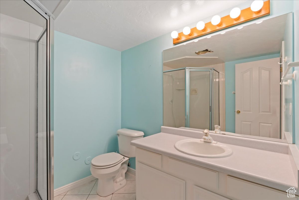 Bathroom with a stall shower, tile patterned floors, vanity, toilet, and baseboards
