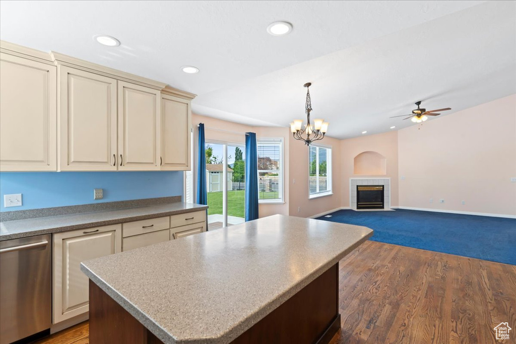Kitchen with dishwasher, cream cabinetry, a fireplace, a ceiling fan, and a center island