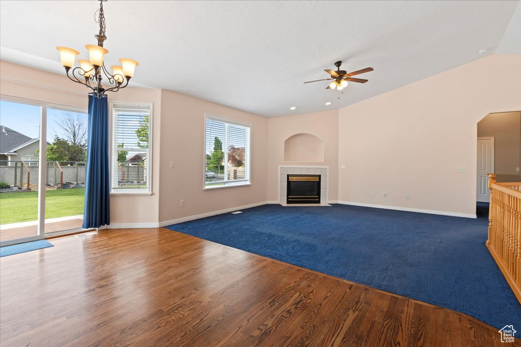 Unfurnished living room featuring a ceiling fan, a chandelier, baseboards, a fireplace, and wood finished floors