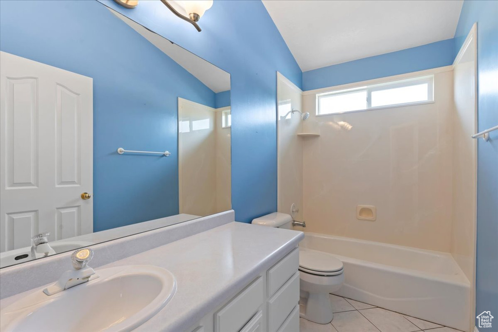 Bathroom featuring vaulted ceiling, toilet, vanity, shower / tub combination, and tile patterned floors