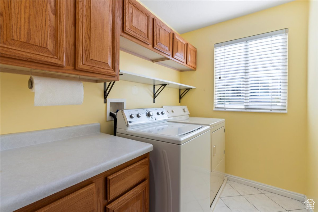 Washroom with washer and dryer, cabinet space, baseboards, and light tile patterned floors
