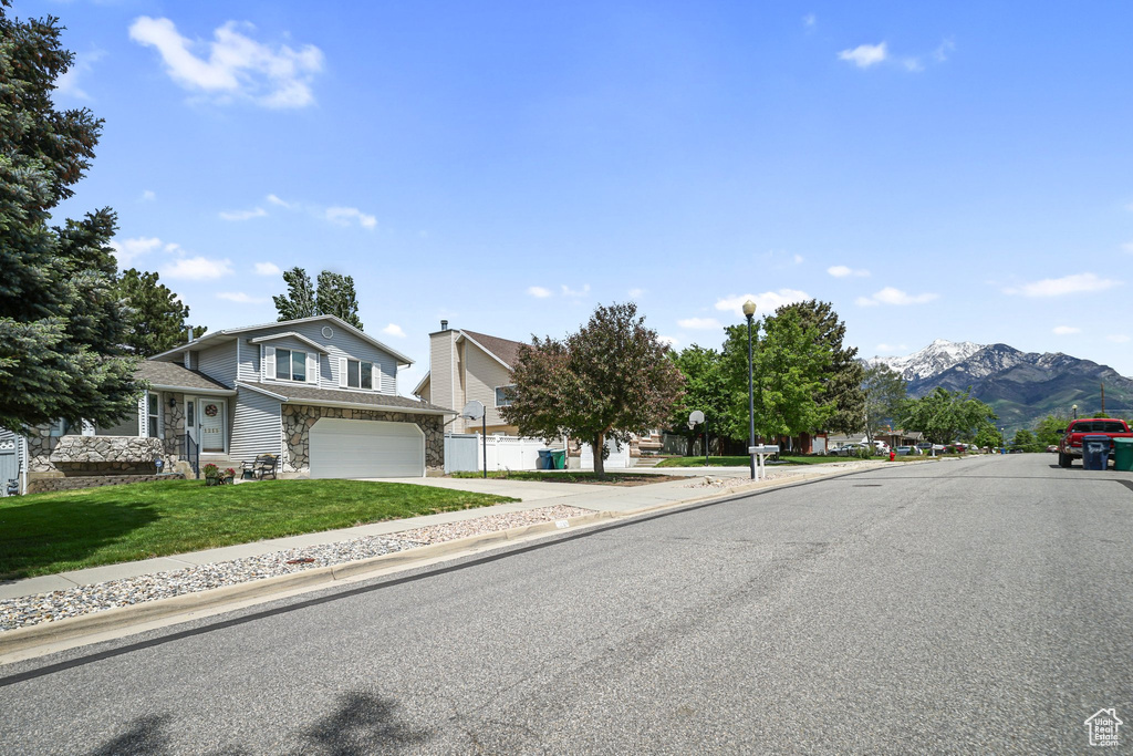 View of asphalt street with sidewalks, street lighting, a mountain view, and curbs