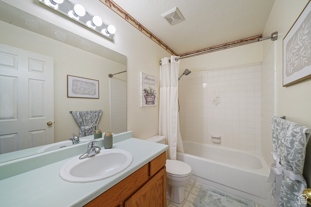 Bathroom featuring shower / bath combination with curtain, vanity, and toilet