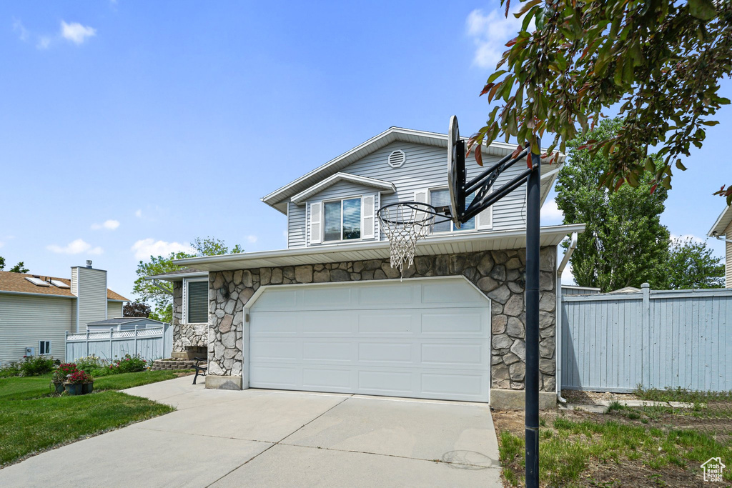 View of front of home featuring stone siding, driveway, and an attached garage