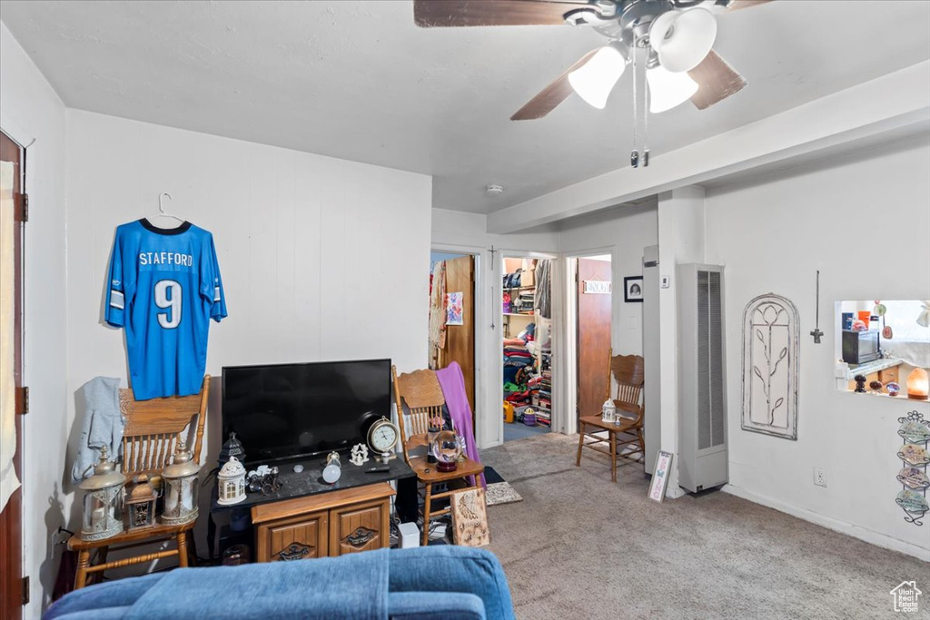 Carpeted living area with a heating unit and a ceiling fan