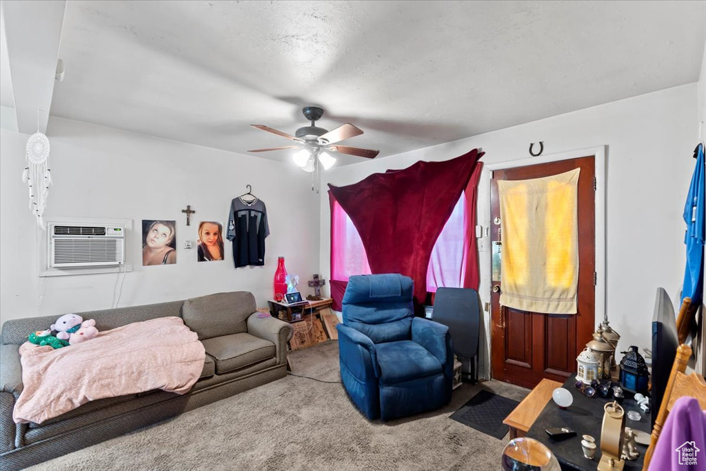 Carpeted living area with ceiling fan and a wall unit AC