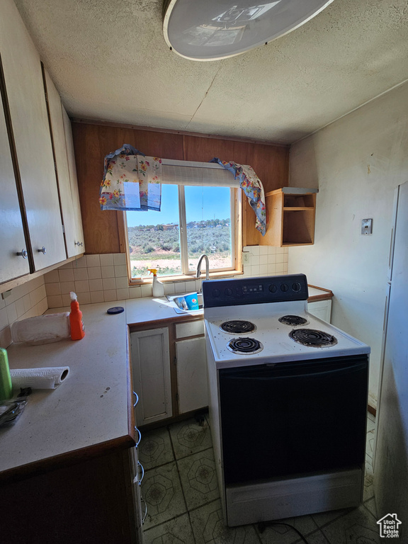 Kitchen with range with electric stovetop, backsplash, a sink, a textured ceiling, and light countertops