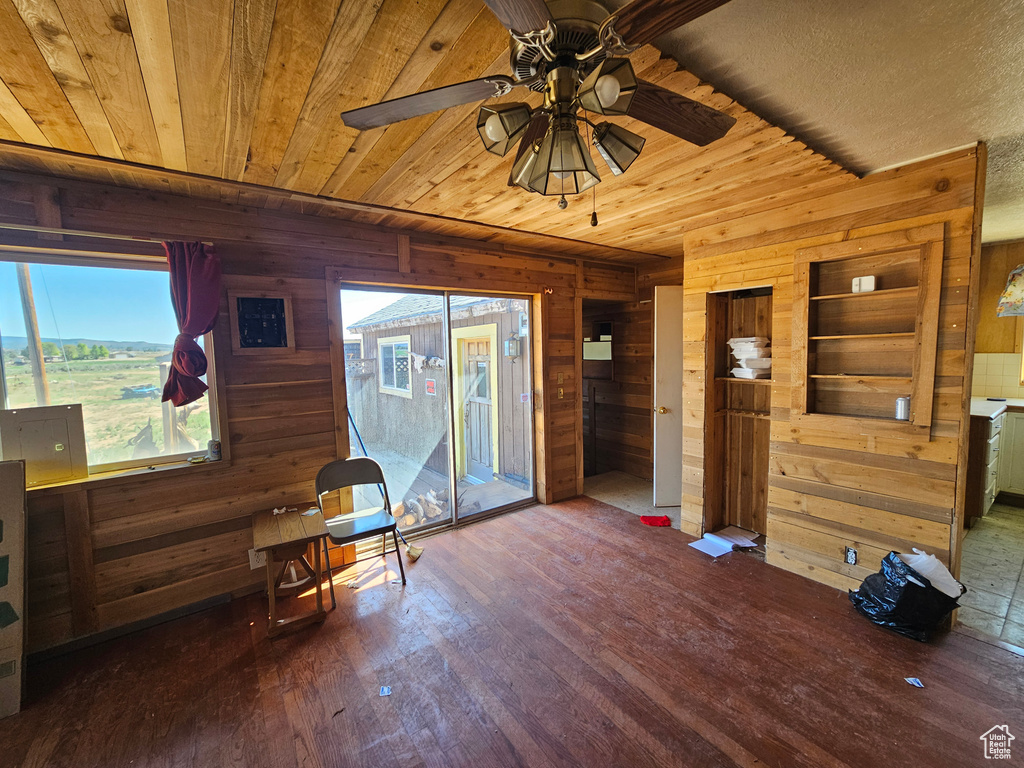 Living area featuring wooden walls, wood finished floors, ceiling fan, and wood ceiling
