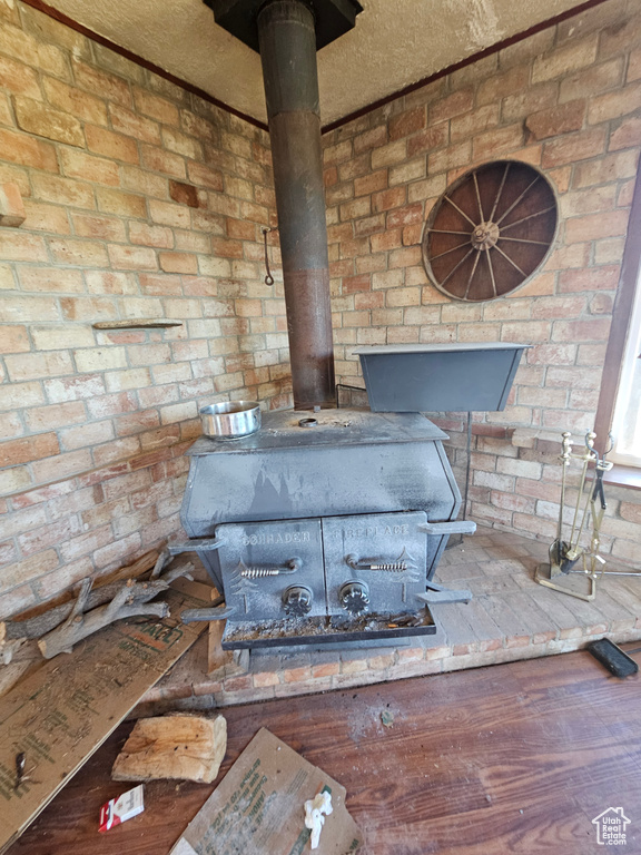Detailed view of a wood stove, wood finished floors, and brick wall