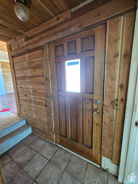 Entryway featuring wood walls, wooden ceiling, and tile patterned floors