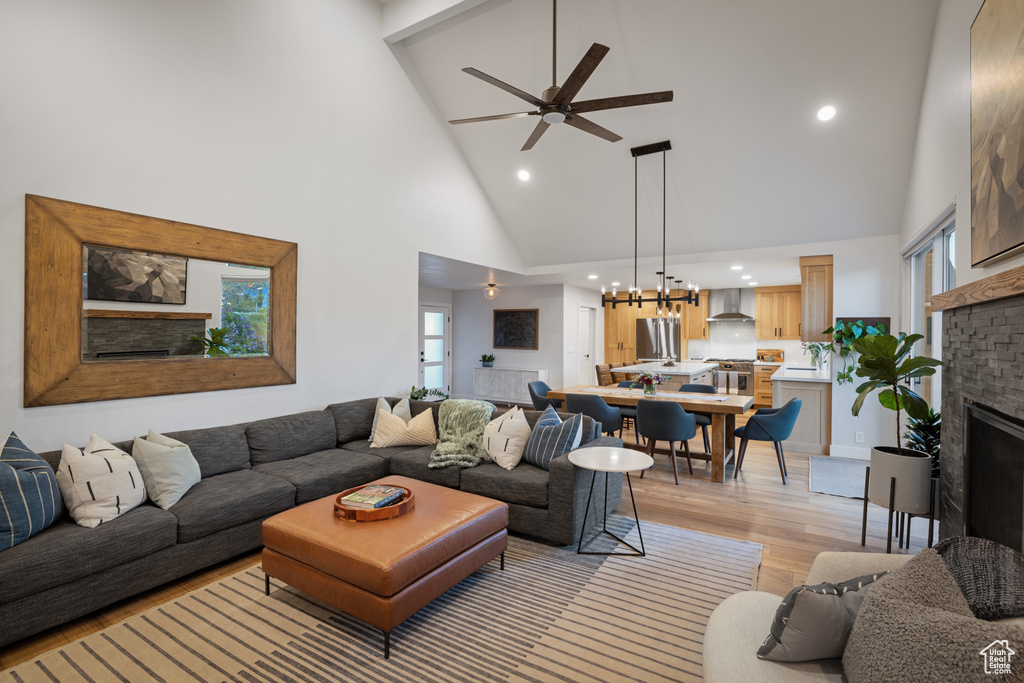 Living area with high vaulted ceiling, a ceiling fan, recessed lighting, light wood finished floors, and a chandelier