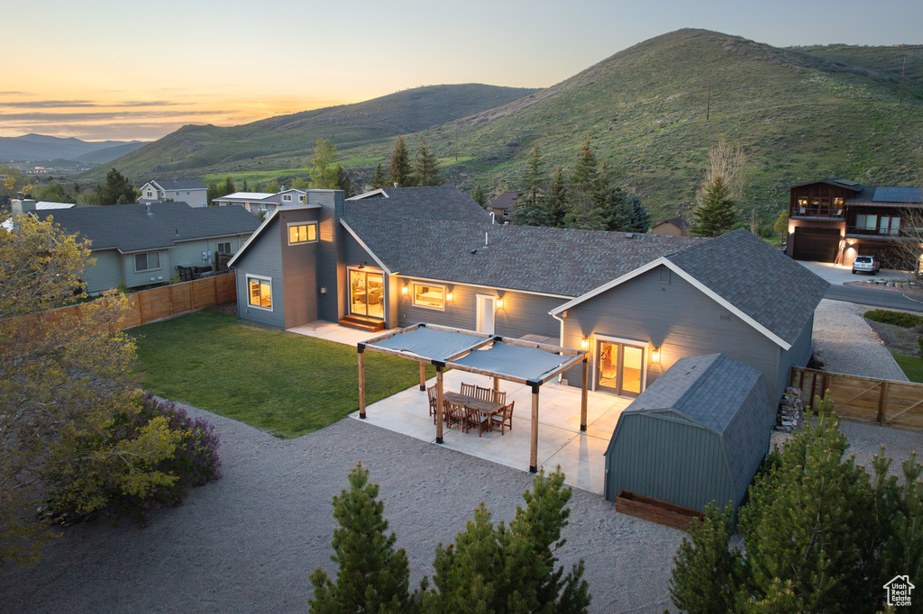 Back of property at dusk with a mountain view, a patio area, and outdoor dining area