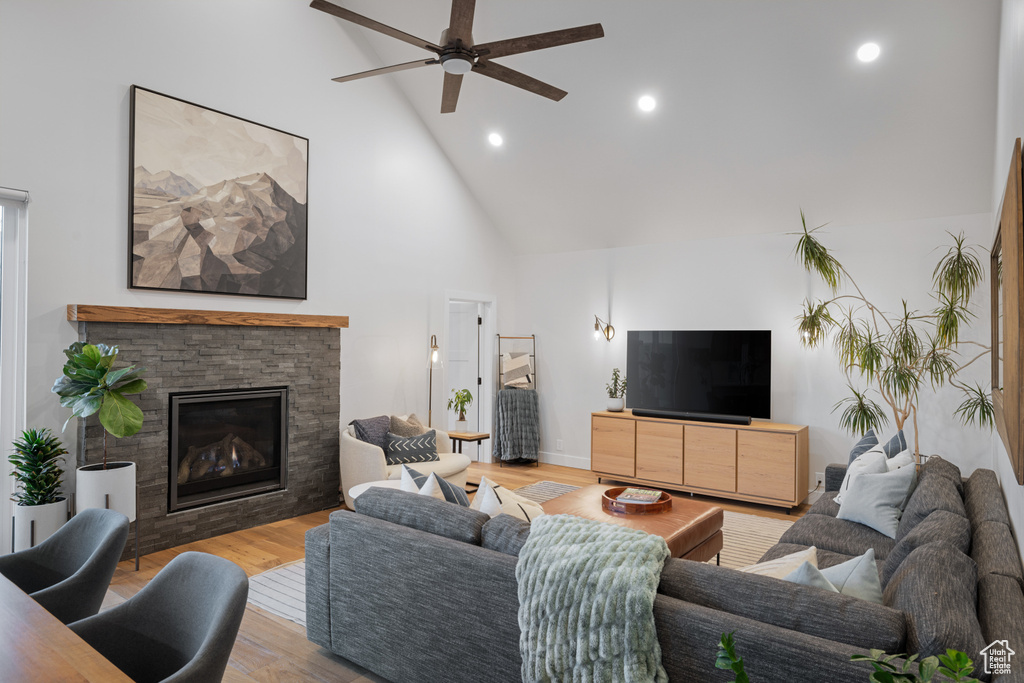 Living room with high vaulted ceiling, a ceiling fan, light wood-type flooring, recessed lighting, and a fireplace
