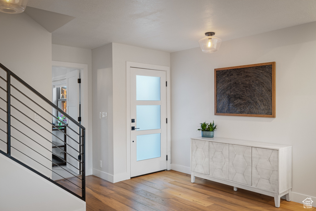 Foyer entrance featuring stairs, wood-type flooring, baseboards, and plenty of natural light