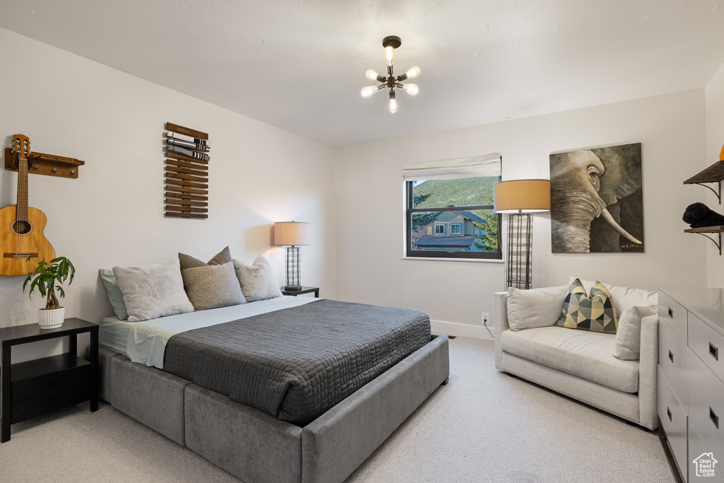 Bedroom featuring light colored carpet, a chandelier, and baseboards
