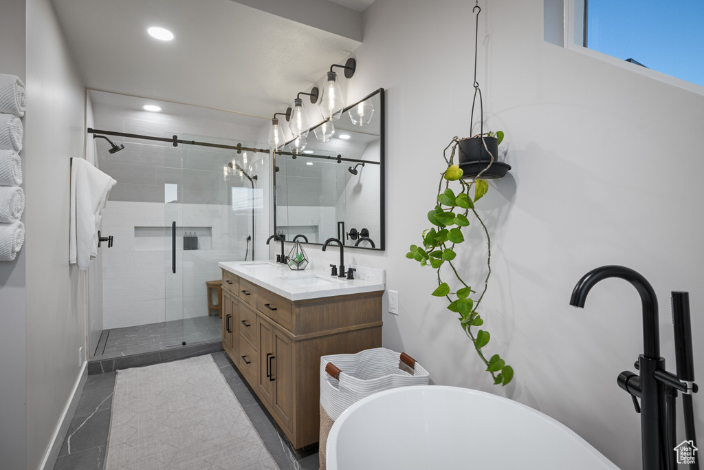 Bathroom featuring double vanity, a shower stall, a soaking tub, recessed lighting, and baseboards