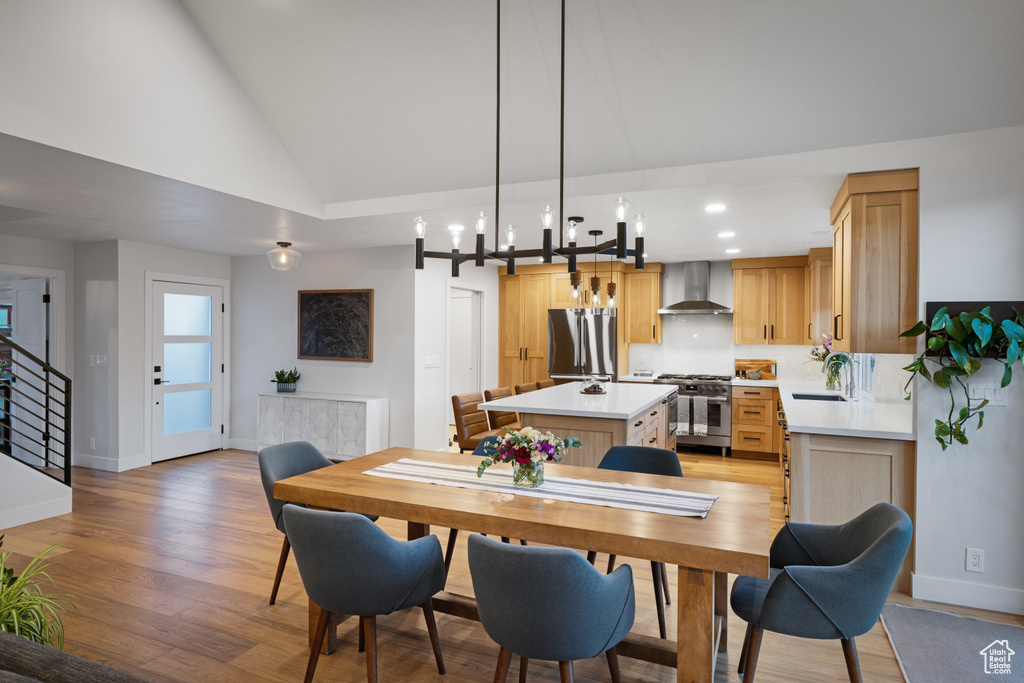 Dining area featuring lofted ceiling, light wood-type flooring, baseboards, recessed lighting, and stairs