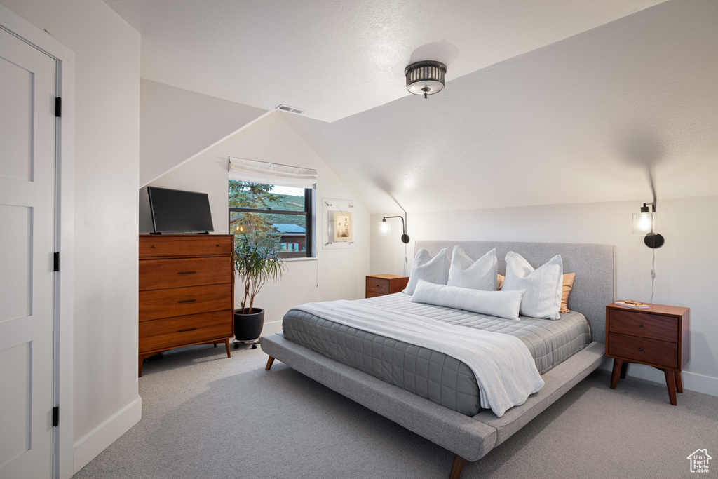 Carpeted bedroom with baseboards and vaulted ceiling