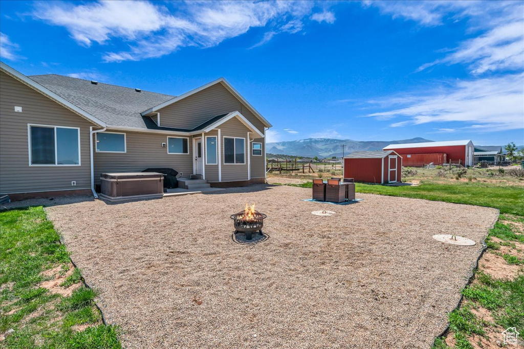 Back of house featuring an outdoor fire pit, a mountain view, and a shingled roof