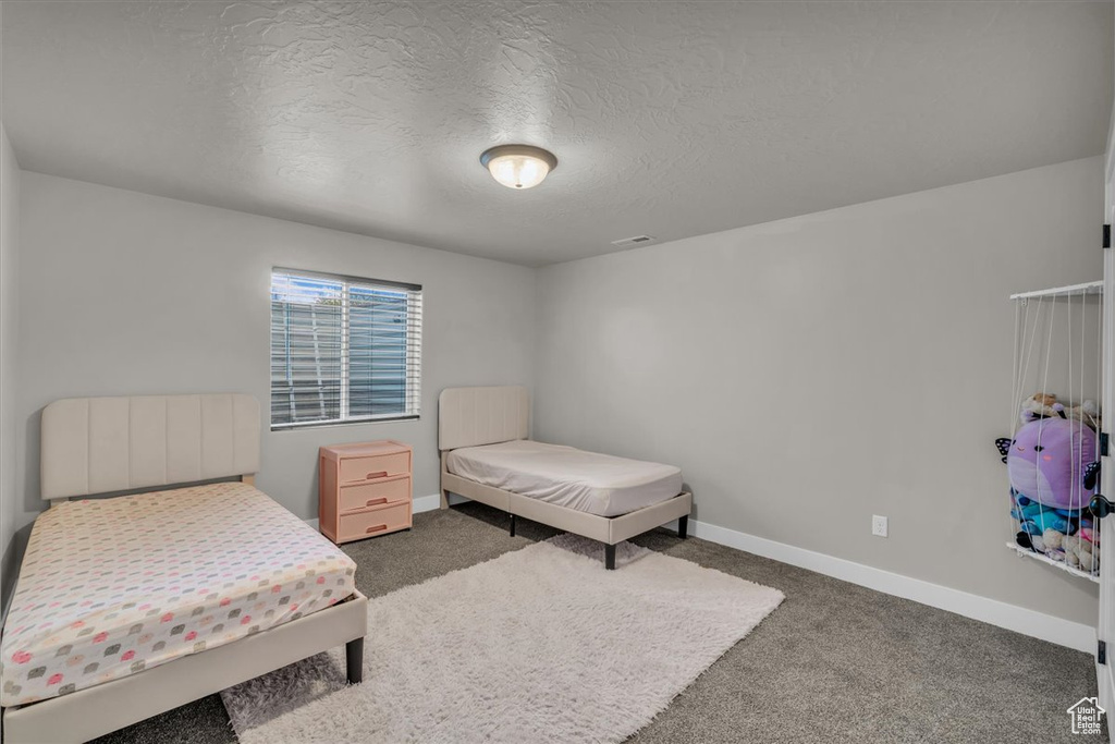 Bedroom with carpet flooring, baseboards, and a textured ceiling