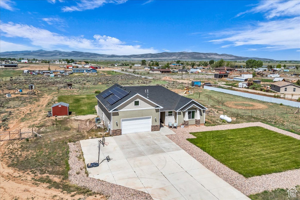 View of front of property featuring a mountain view, concrete driveway, a front yard, and a garage