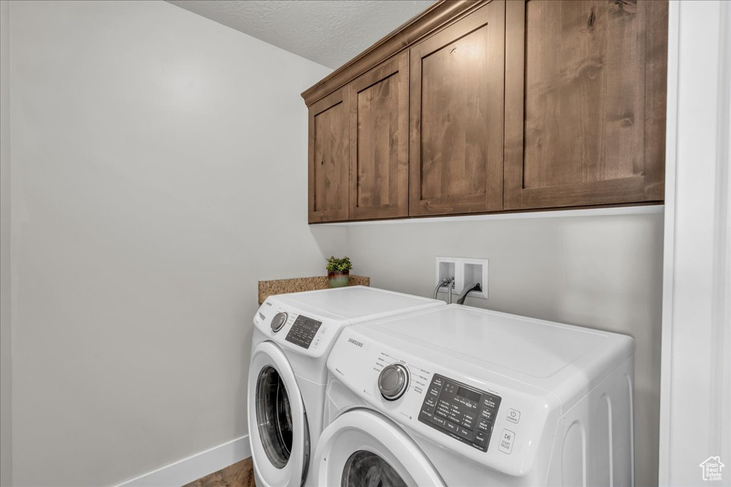 Washroom featuring cabinet space, separate washer and dryer, and baseboards
