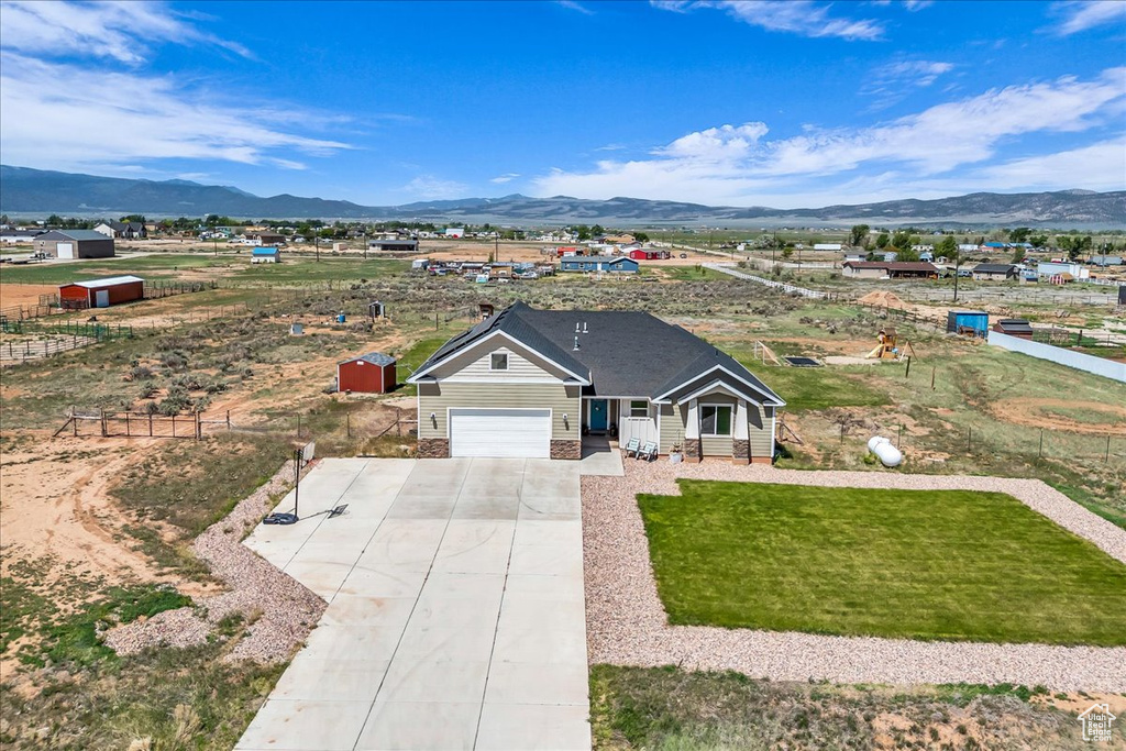 Ranch-style home featuring a mountain view, concrete driveway, a garage, and a front yard