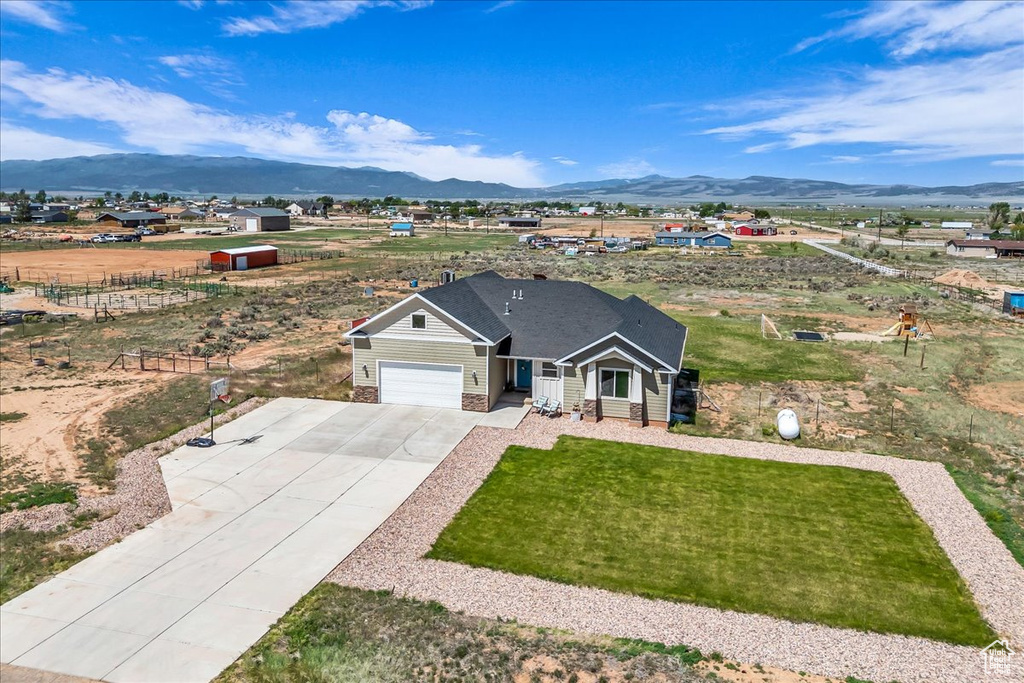 View of front of house with a mountain view, concrete driveway, a garage, and a front yard