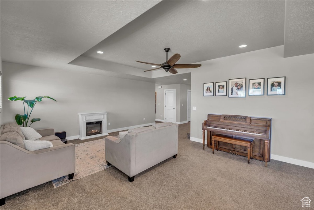Carpeted living room with a textured ceiling, baseboards, a ceiling fan, recessed lighting, and a glass covered fireplace