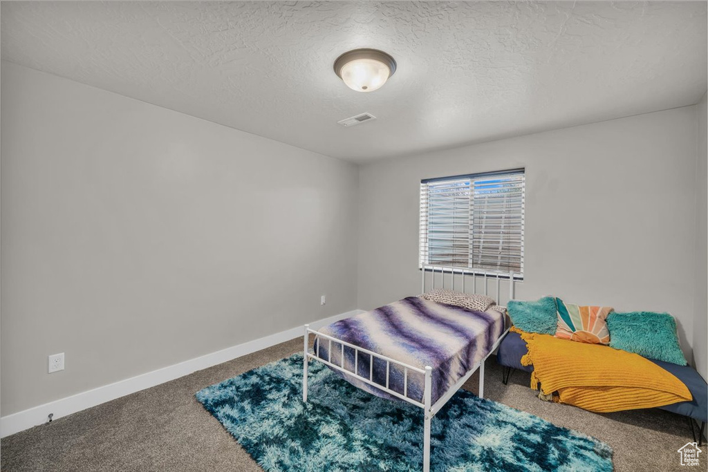 Carpeted bedroom with baseboards and a textured ceiling