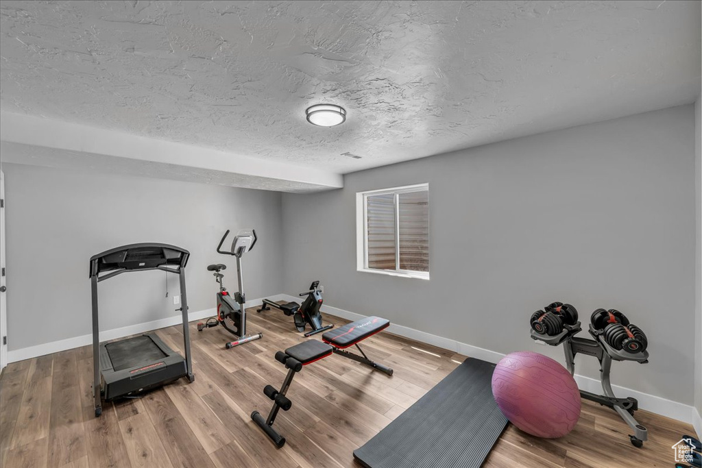 Exercise area featuring baseboards, wood finished floors, and a textured ceiling