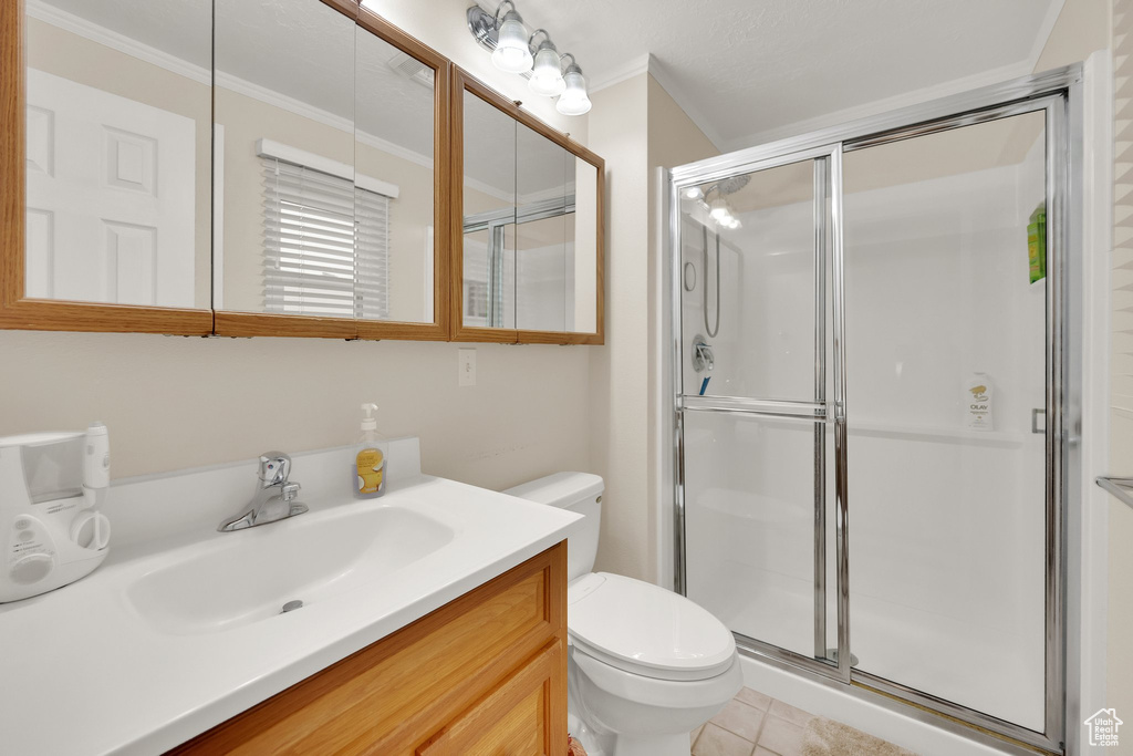 Bathroom featuring toilet, vanity, a shower stall, crown molding, and tile patterned flooring