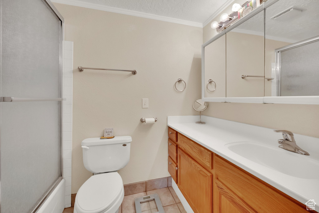 Bathroom featuring vanity, toilet, tile patterned floors, crown molding, and baseboards