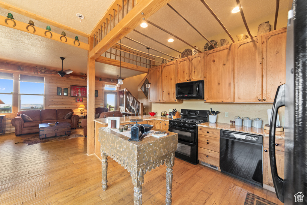 Kitchen featuring black appliances, plenty of natural light, light wood finished floors, ceiling fan, and a textured ceiling