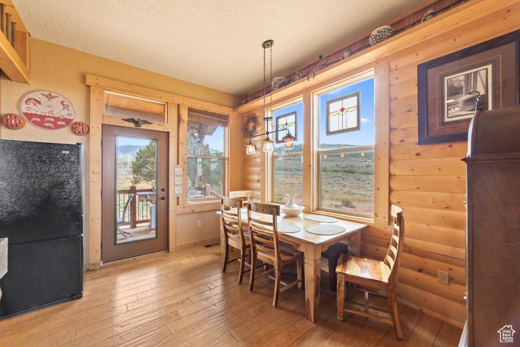 Dining space with light wood-style flooring, log walls, and a textured ceiling