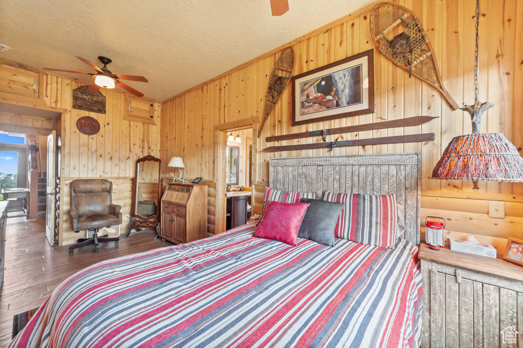 Bedroom featuring wooden walls, wood finished floors, and a textured ceiling