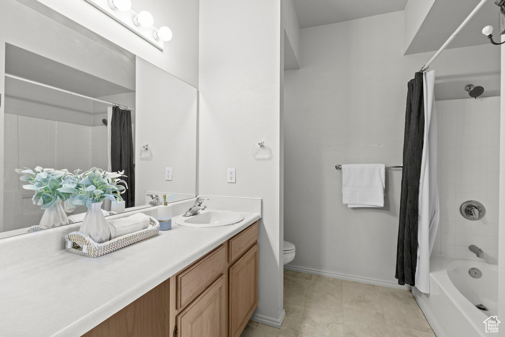 Full bathroom featuring vanity, shower / tub combo, toilet, and baseboards