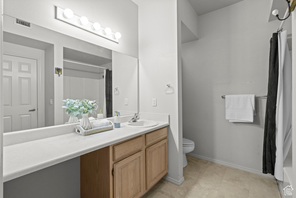 Bathroom with vanity, toilet, a shower with curtain, baseboards, and tile patterned floors