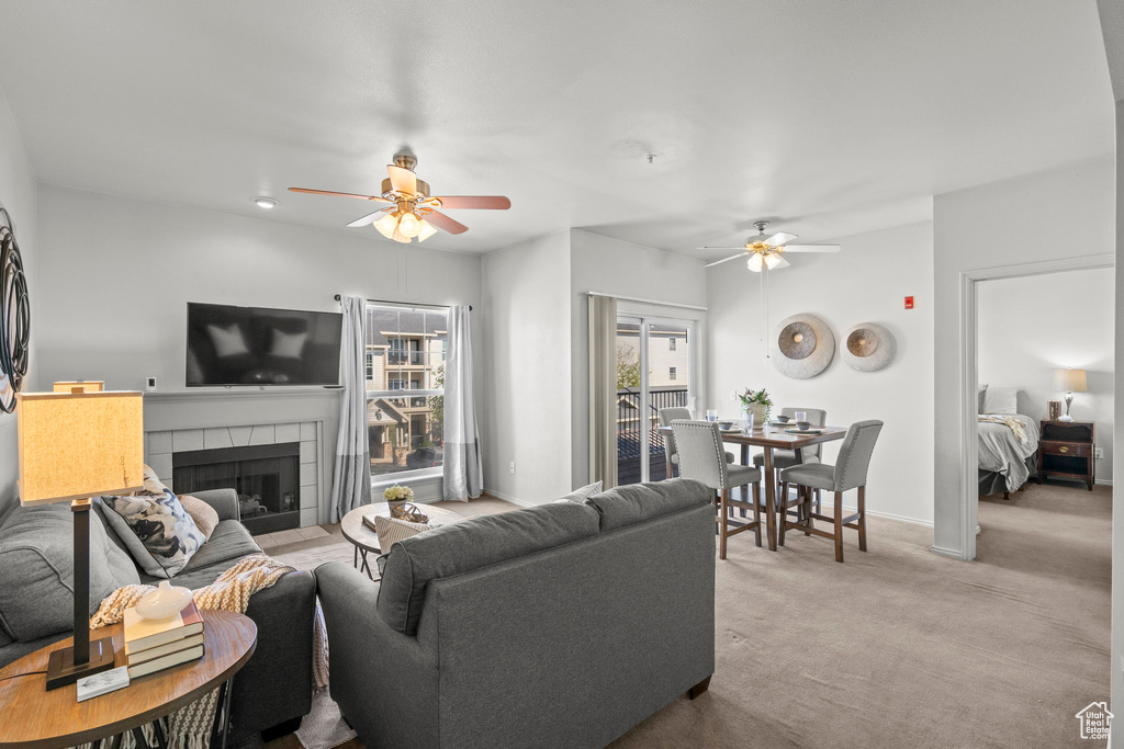Carpeted living area with ceiling fan, a fireplace, and baseboards