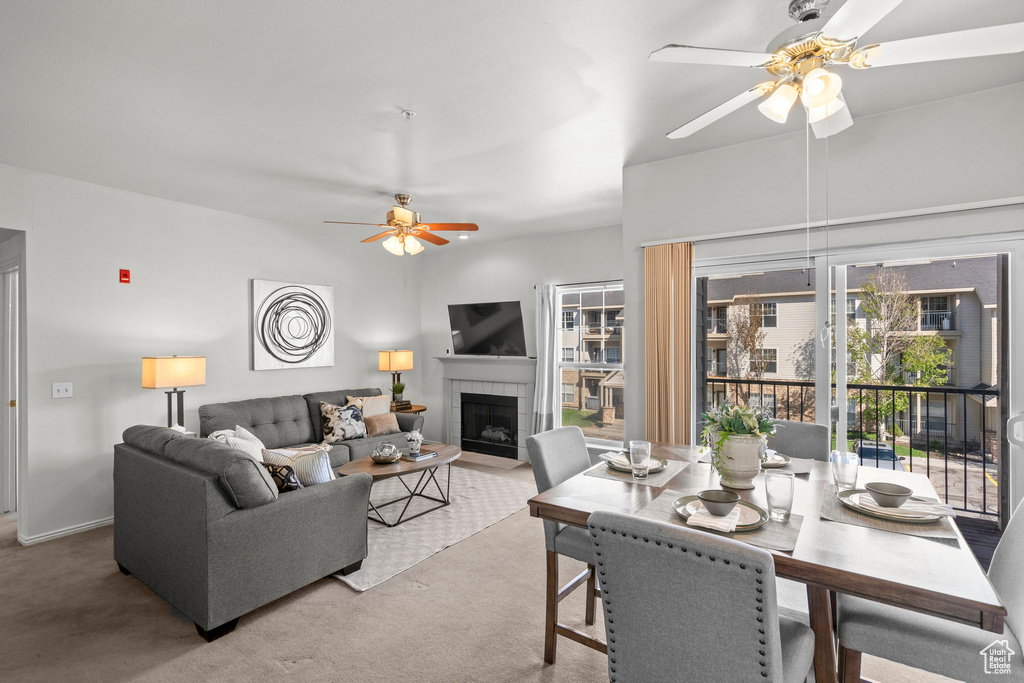 Living room with a ceiling fan, a tile fireplace, carpet, and healthy amount of natural light