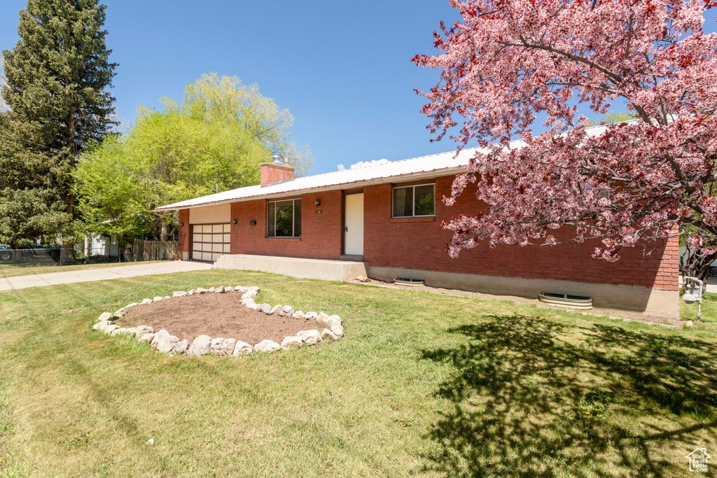 Single story home with a chimney, an attached garage, concrete driveway, and brick siding