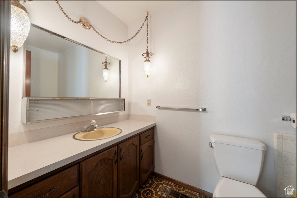 Bathroom with toilet, vanity, and baseboards