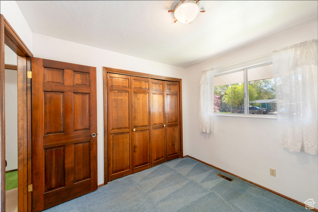 Unfurnished bedroom with dark colored carpet, a closet, and baseboards