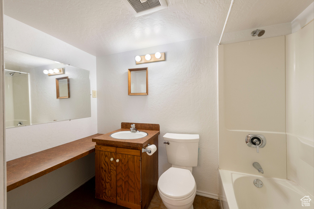 Full bath featuring vanity, toilet,  shower combination, and a textured ceiling