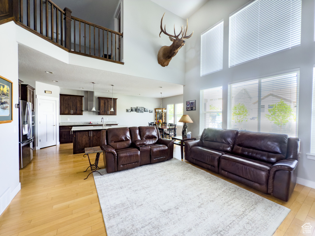 Living area with a high ceiling, light wood-style flooring, and baseboards