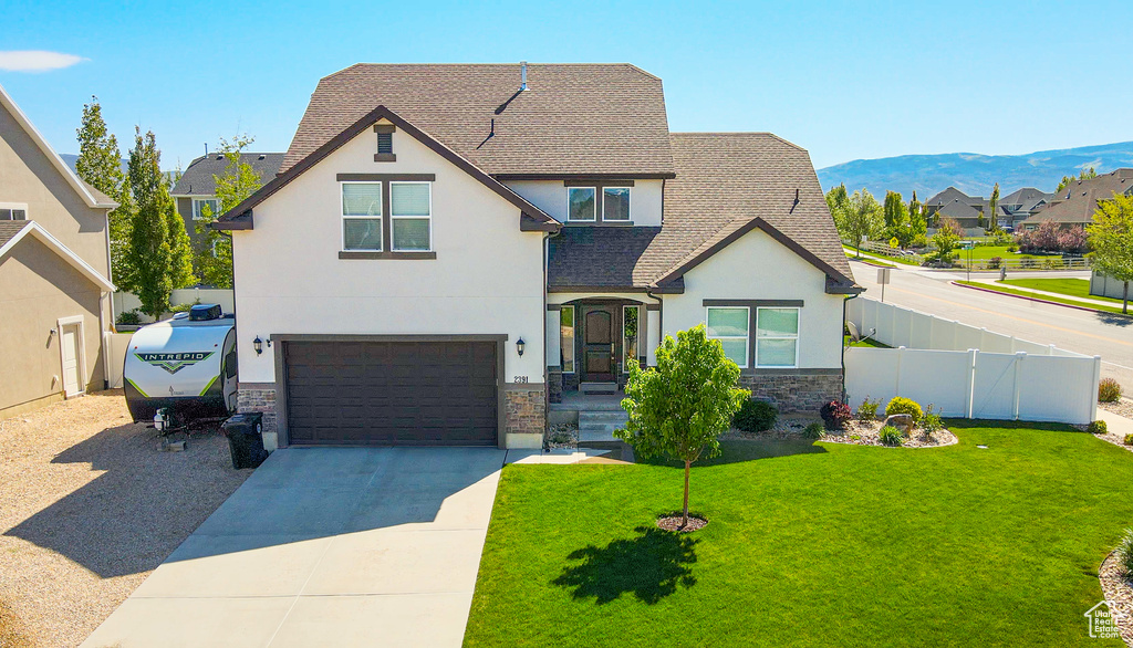 View of front of house with stucco siding, stone siding, an attached garage, driveway, and a mountain view