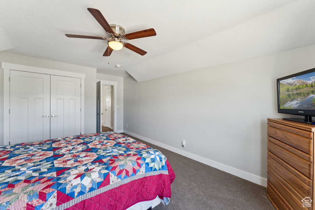 Carpeted bedroom with baseboards, a closet, a ceiling fan, and vaulted ceiling