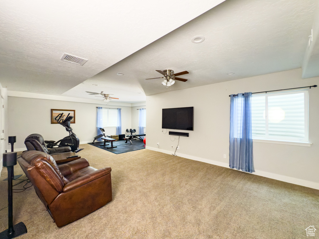 Living area featuring baseboards, carpet floors, and a ceiling fan