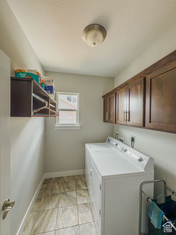 Laundry room with separate washer and dryer, cabinet space, baseboards, light marble finish floors, and a textured ceiling