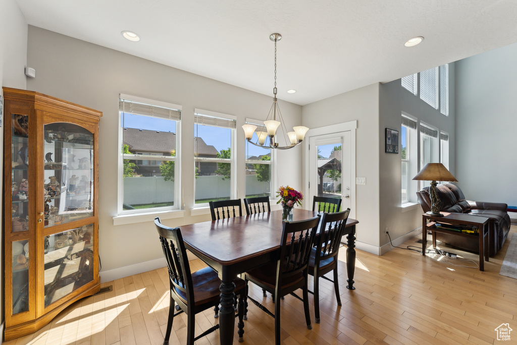 Dining room with a chandelier, baseboards, light wood-style flooring, and recessed lighting